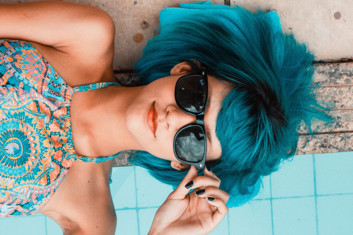 meisje met groen haar aan het zwembad met zonnebril