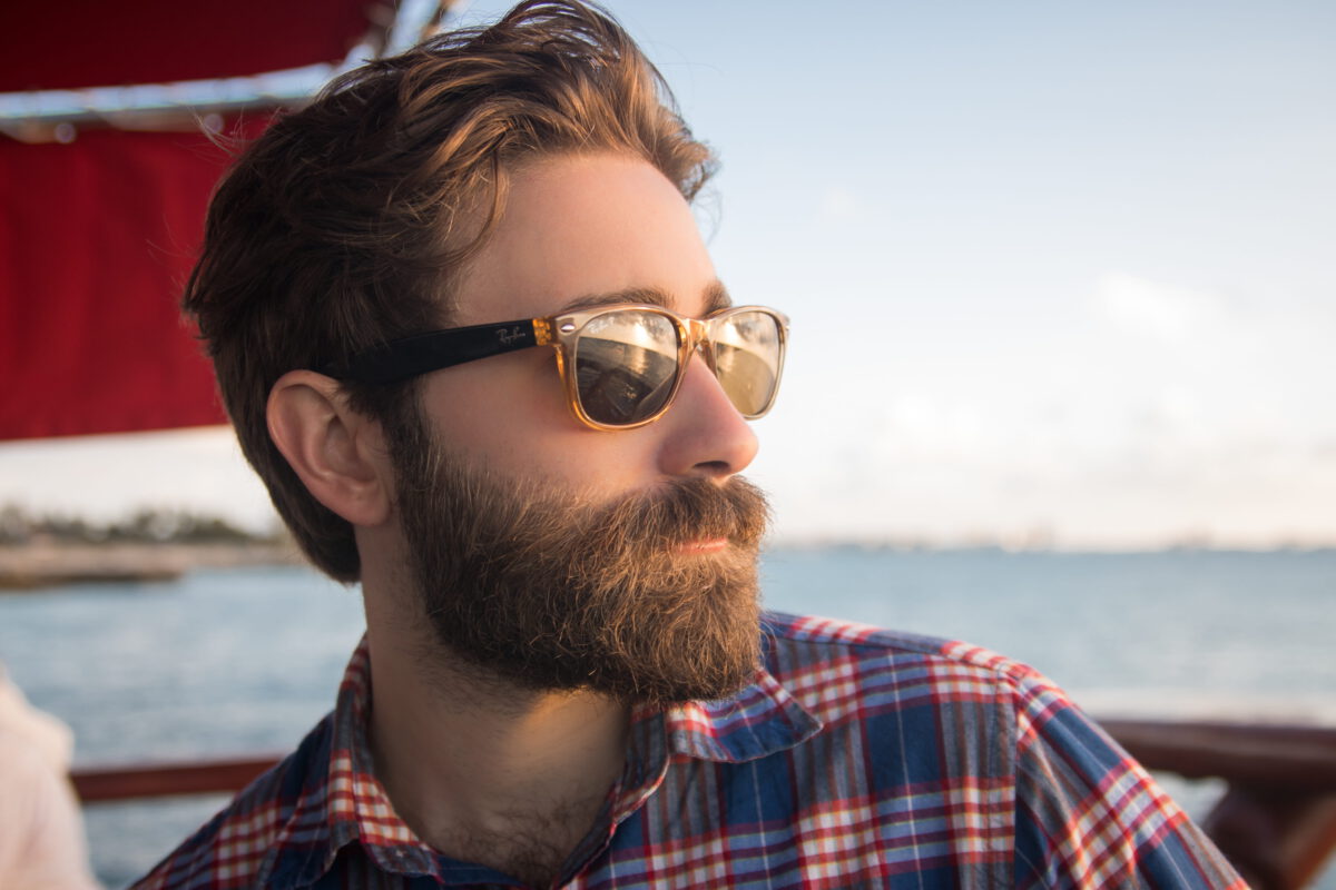 man met baard en zonnebril op zeilboot