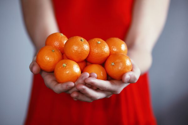 vrouw in jurk houd mandarijnen vast