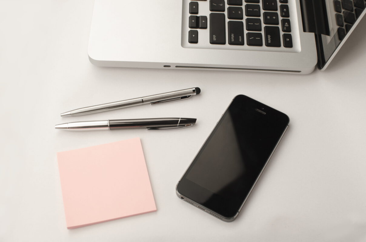 laptop, pennen, notitieblokje en iPhone